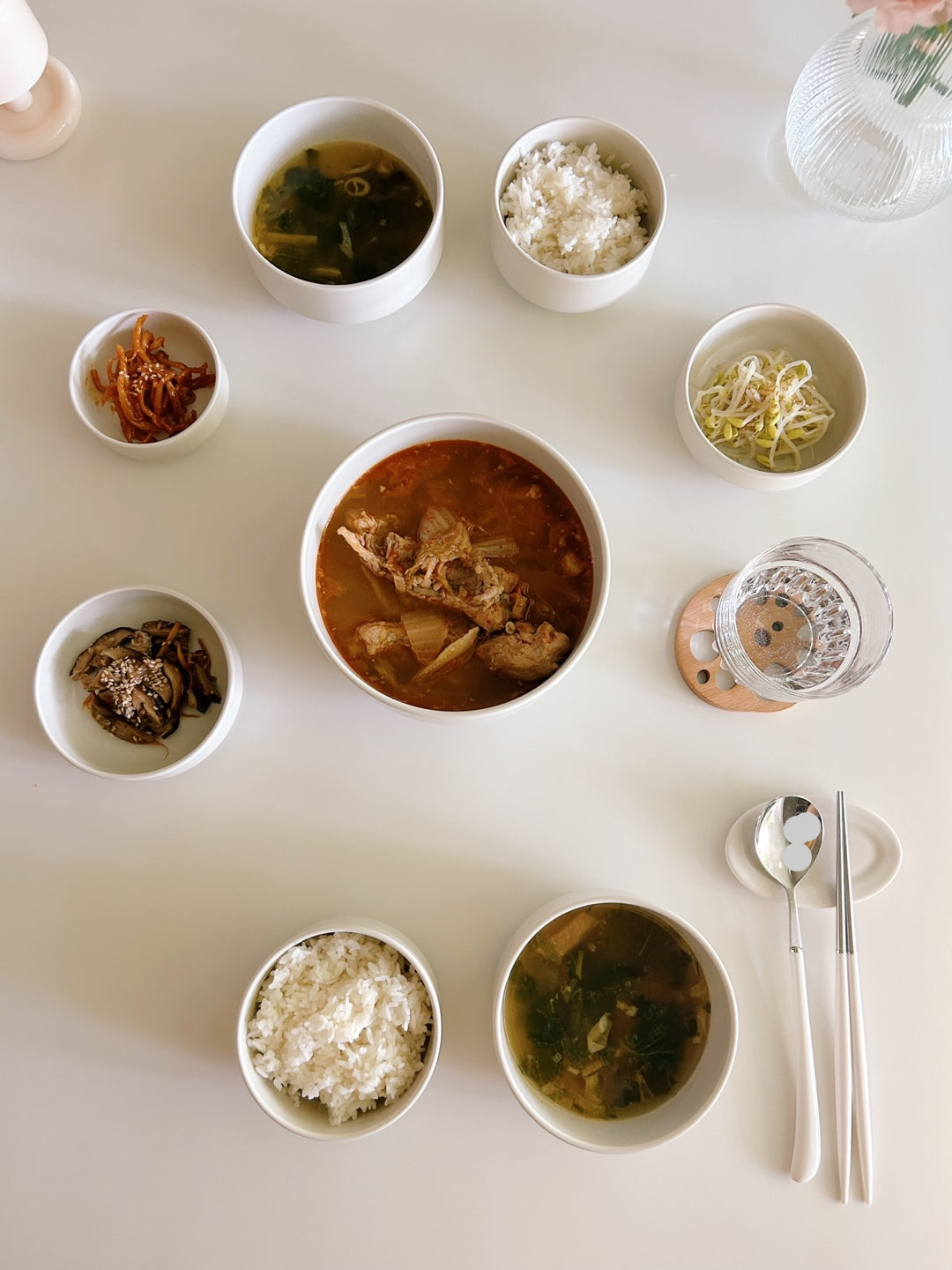 Assorted Korean dishes including soup, rice, and side dishes on a white table.