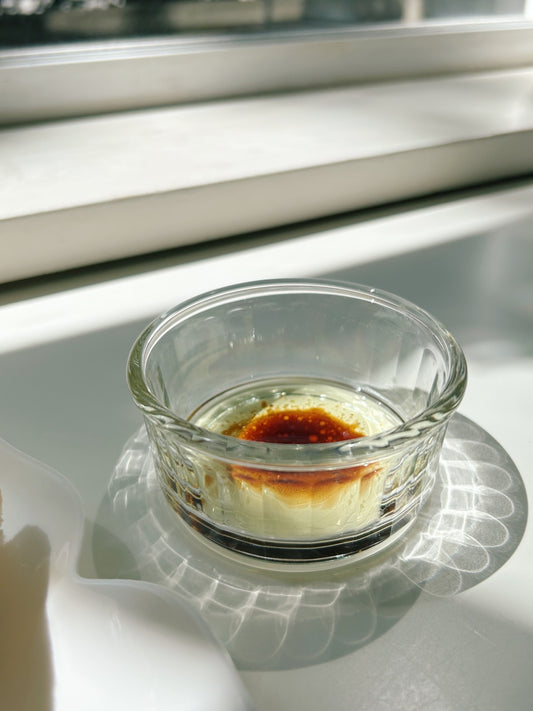 Small glass dish with a baked custard on a white surface