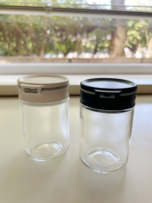 Two clear glass jars with lids on a light surface.